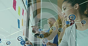 Image of network of connections with globe icons over diverse business people in office