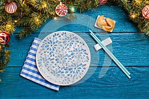Image of New Year branches of fir, cookies with prediction, plates, sticks for sushi
