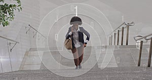 Image of numbers over african american businesswoman talking on smartphone while climbing stairs photo