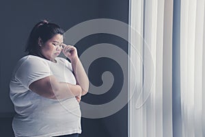 Obese woman thinking something near the window