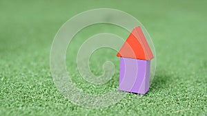 Image of rectangular and triangular shape wood block forming shape of a house on green grass