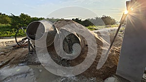 an old cement mixer machine by the pile of sand at the construction site.