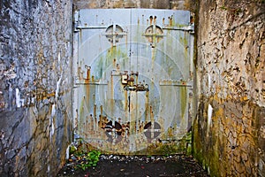 Old mine entrance with cement walls and huge steel door rusting