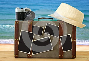 Image of old vintage luggage, fedora hat, vintage old photo camera and blank photos for photography montage mockup over wooden flo