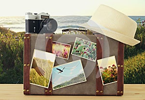 Image of old vintage luggage, fedora hat and vintage old photo camera with nature photos over wooden floor.
