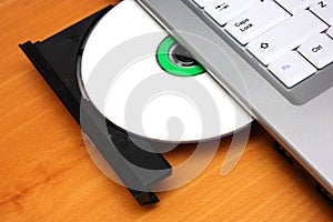 Image of an optical disc being inserted into a laptop's drive.