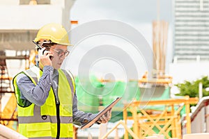 Image outside the industrial construction engineers in yellow protective helmet discuss new project while walkie talkie