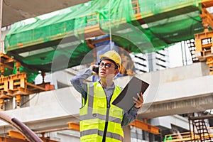 Image outside the industrial construction engineers in yellow protective helmet discuss new project while walkie talkie