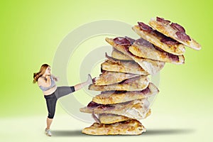 Overweight woman kicking a pile of pizzas