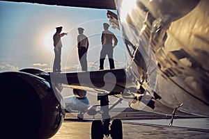 Image of part of aircraft standing in the airport with flight staff