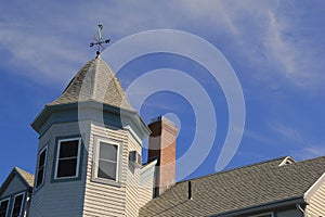 Image of peaks of roof and weathervane with brilliant blue skies beyond