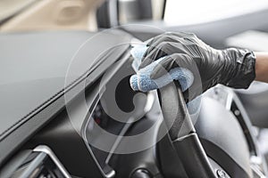 This image is a picture of wiping the car by a blue microfiber cloth with hand wearing gloves