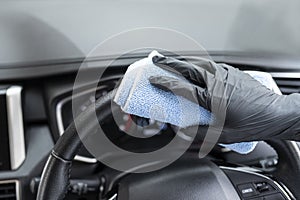 This image is a picture of wiping the car by a blue microfiber cloth with hand wearing gloves