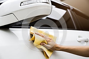This image is a picture of wiping the car with a yellow microfiber cloth by hand.