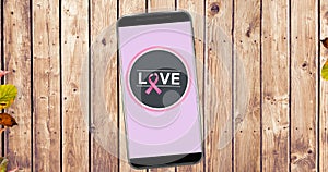 Image of pink breast cancer ribbon logo with love text on smartphone screen