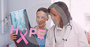Image of pink breast cancer ribbon over two female smiling doctors