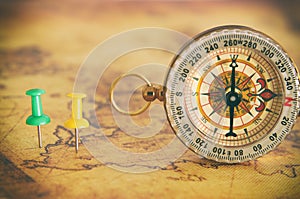 Image of pins attached to map, showing location or travel destination next to vintage compass. selective focus.