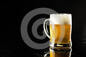 Image of pint glass tankard of foamy beer, with copy space on black background