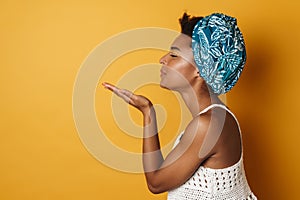 Image of pleased african american woman blowing air kiss aside