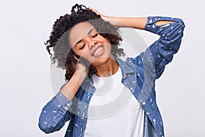 Image of pleased dark-skinned young woman dressed in blue shirt, holding hands on head, feels happy. African American female