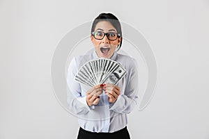 Image of pleased secretary woman wearing eyeglasses holding bunch of money in the office, isolated over white background