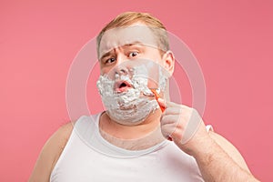 Image of plump shocked amazed man with shaving foam on face. Looking at camera.
