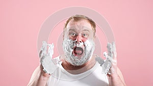 Image of plump shocked amazed man with shaving foam on face. Looking at camera, slow motion.