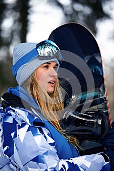 Image with a portrait of a female snowboarder wearing a helmet with a bright reflection in the glasses. On the