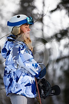 Image with a portrait of a female snowboarder wearing a helmet with a bright reflection in the glasses. On the