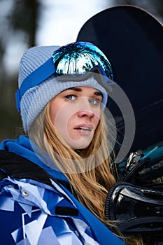 Image with a portrait of a female snowboarder wearing a helmet with a bright reflection in the glasses. On the