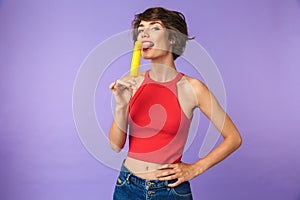 Image of positive cute woman 20s in casual wear smiling and eating ice cream, isolated over violet background