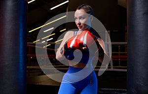 Image of a powerful sportswoman wrestler. Posing in a blue tracksuit and red boxing gloves. The concept of wrestling and boxing