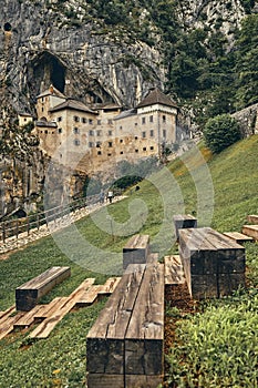 Image of Predjamski castle with benches in the foreground