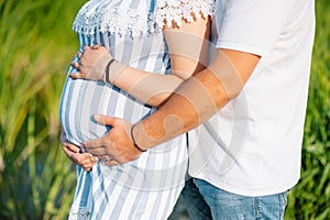 Image of pregnant couple. Husband touching his wife belly with hands. Pregnant woman outdoors.