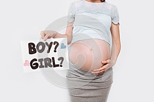 Image of a pregnant woman holding a paper near the pregnant belly, with a boy or girl issues
