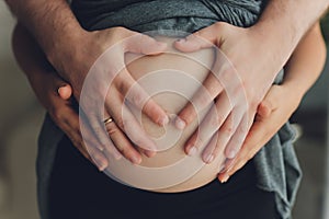 Image of pregnant woman touching her belly with hands.