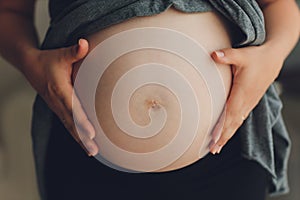 Image of pregnant woman touching her belly with hands.