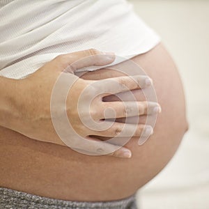 Image of pregnant woman touching her hearth with hands