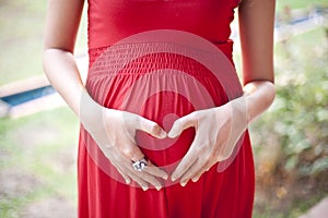 Image of pregnant woman touching her hearth with hands