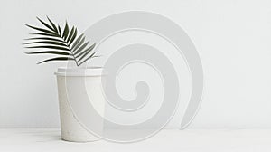 A white coffee cup with a green leaf in it.