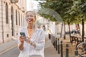 Image of pretty cheerful woman at the city with phone