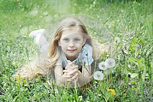 Image of pretty little girl lying down on dandelions field