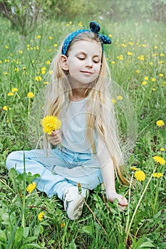 Image of pretty little girl sitting on dandelions field