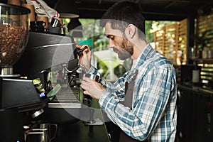 Image of professional barista man making coffee while working in cafe or coffeehouse outdoor