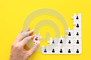 Image of puzzle pieces with people icons over yellow background ,human resources social distancing and management concept