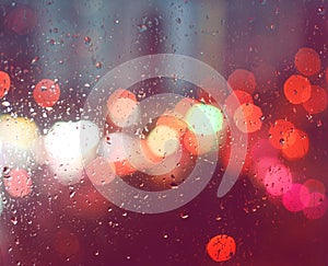 Image of raindrops on window at night in the city