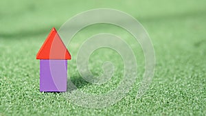 Image of rectangular and triangular shape wood block forming shape of a house on green grass