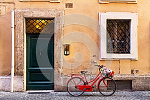 Image of a red bicycle on an old narrow cobblestone street in Rome, Italy