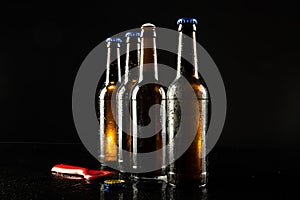 Image of red bottle opener and four beer bottles one open, with copy space on black