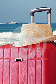 Image of red elegant travel luggage and fedora hat in front of sea. travel and vacation concept